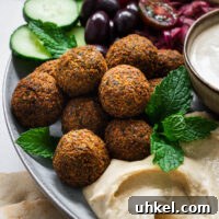 Crispy Authentic Middle Eastern Falafel Recipe 13 Golden brown Middle Eastern falafel on a plate with tahini sauce, hummus and fresh salad.