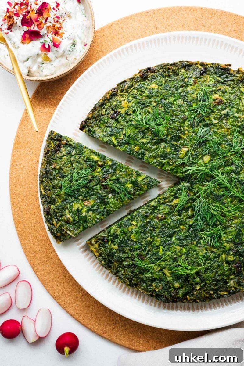 Crispy Authentic Middle Eastern Falafel Recipe 15 A large circular baked kuku sabzi with a beautiful green top viewed from above, next to a small bowl with Persian cucumber yoghurt.