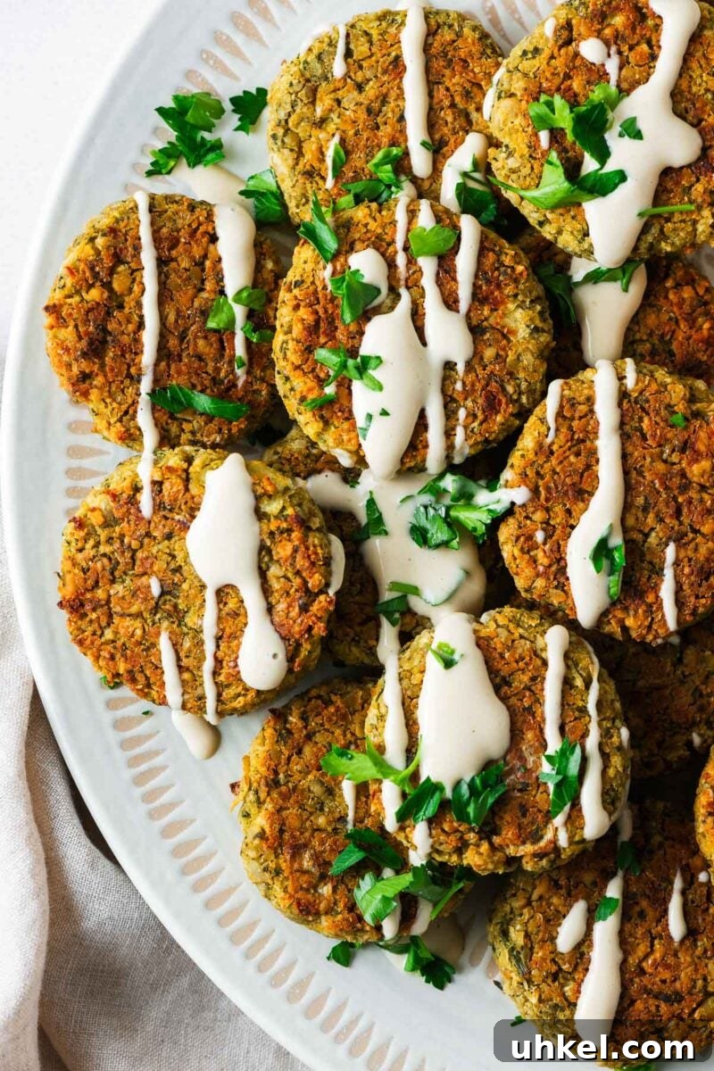 Crispy Authentic Middle Eastern Falafel Recipe 17 Top down view of a serving bowl with baked falafel made with canned chickpeas drizzled with tahini sauce.