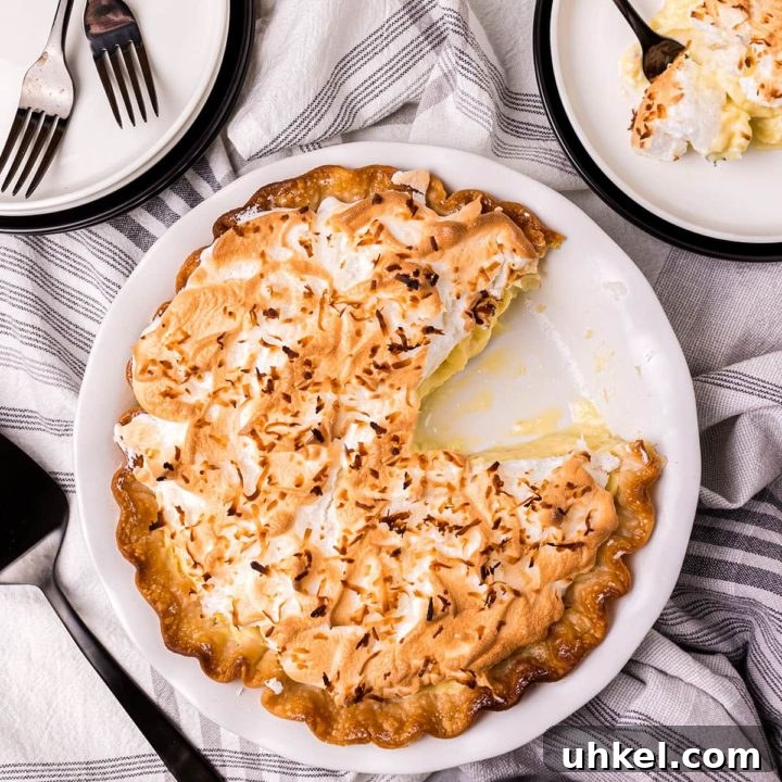 coconut pie with one serving on a plate with a fork