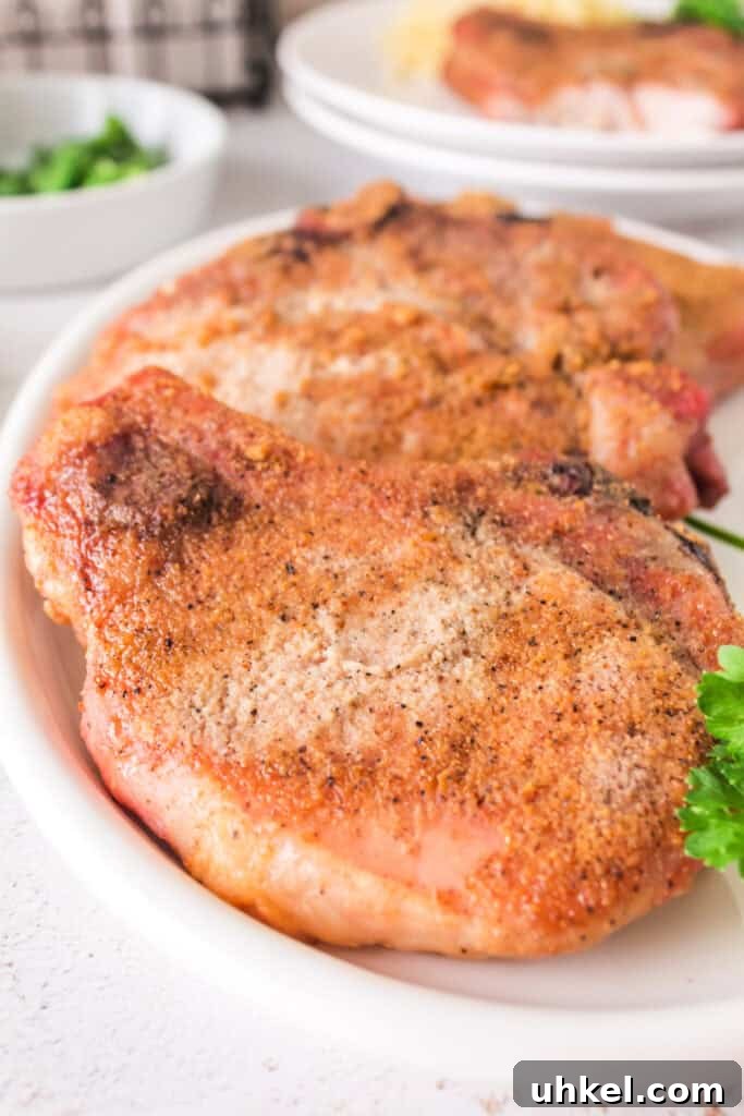 Smoked Pork Chops Recipe: Tender, Juicy Flavor from the Smoker 2 Close-up of plated smoked pork chops on a white serving dish with parsley