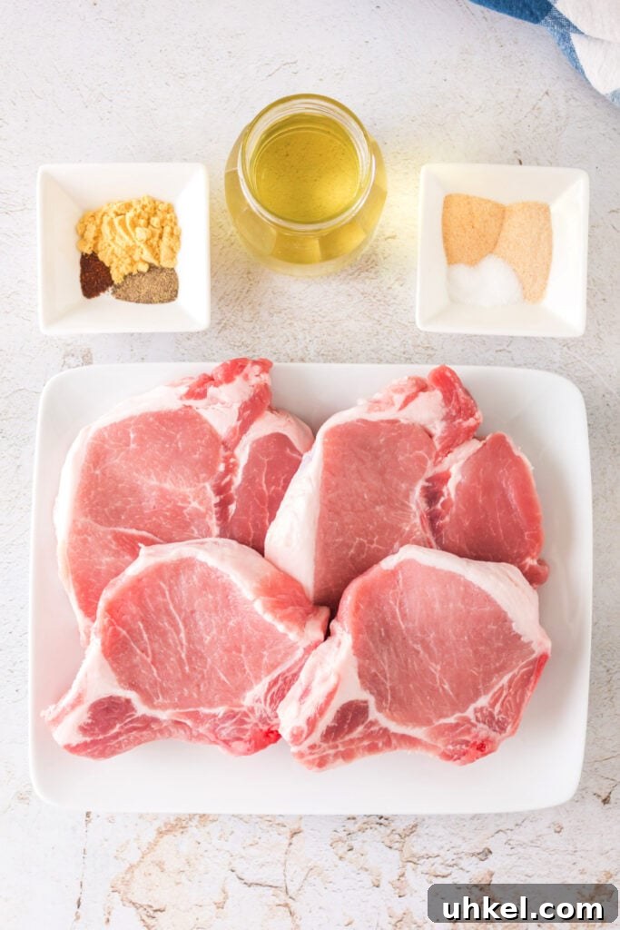 Smoked Pork Chops Recipe: Tender, Juicy Flavor from the Smoker 3 Raw bone-in pork chops on a white plate with seasoning bowls and oil nearby