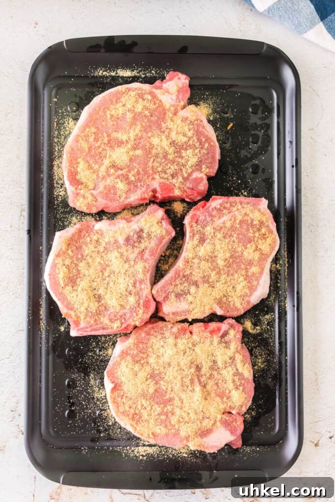Smoked Pork Chops Recipe: Tender, Juicy Flavor from the Smoker 7 Pork chops on a black tray coated evenly with the dry rub
