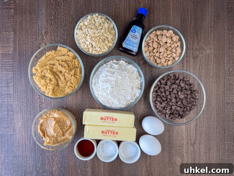 Gooey Chocolate Peanut Butter Oatmeal Bars Recipe 4 Ingredients to make gooey cookie bars are old fashioned oats, vanilla, peanut butter chips, flour, chocolate chips, eggs, butter, baking soda, salt, peanut butter and brown sugar on a wooden counter top.