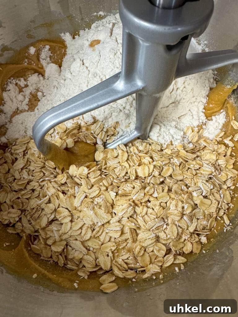 Gooey Chocolate Peanut Butter Oatmeal Bars Recipe 7 Mixer beater in a bowl with peanut butter, old fashioned oats and flour.