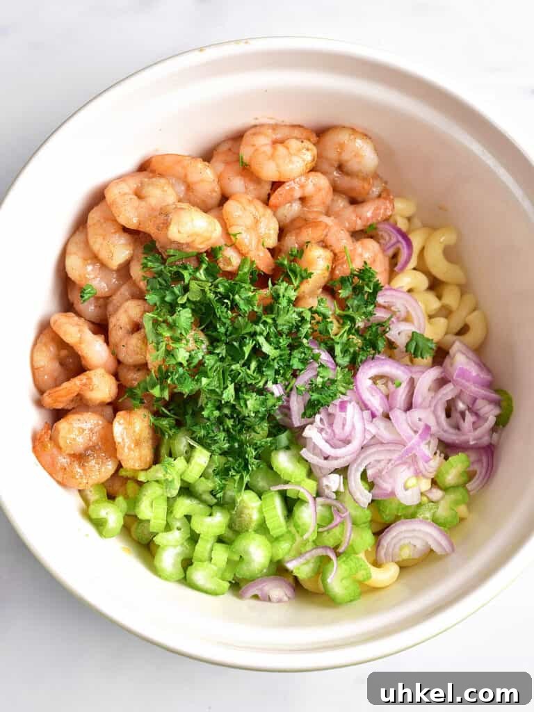 Lemon Garlic Shrimp Pasta Salad with Fresh Herbs 5 Shrimp, celery, shallots, parsley and pasta in a white bowl. Top view.