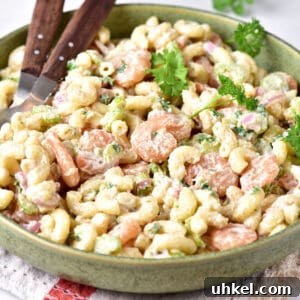 Lemon Garlic Shrimp Pasta Salad with Fresh Herbs 8 Pasta salad with shrimp on a green plate. Parsley leaves, wooden serving utensils.