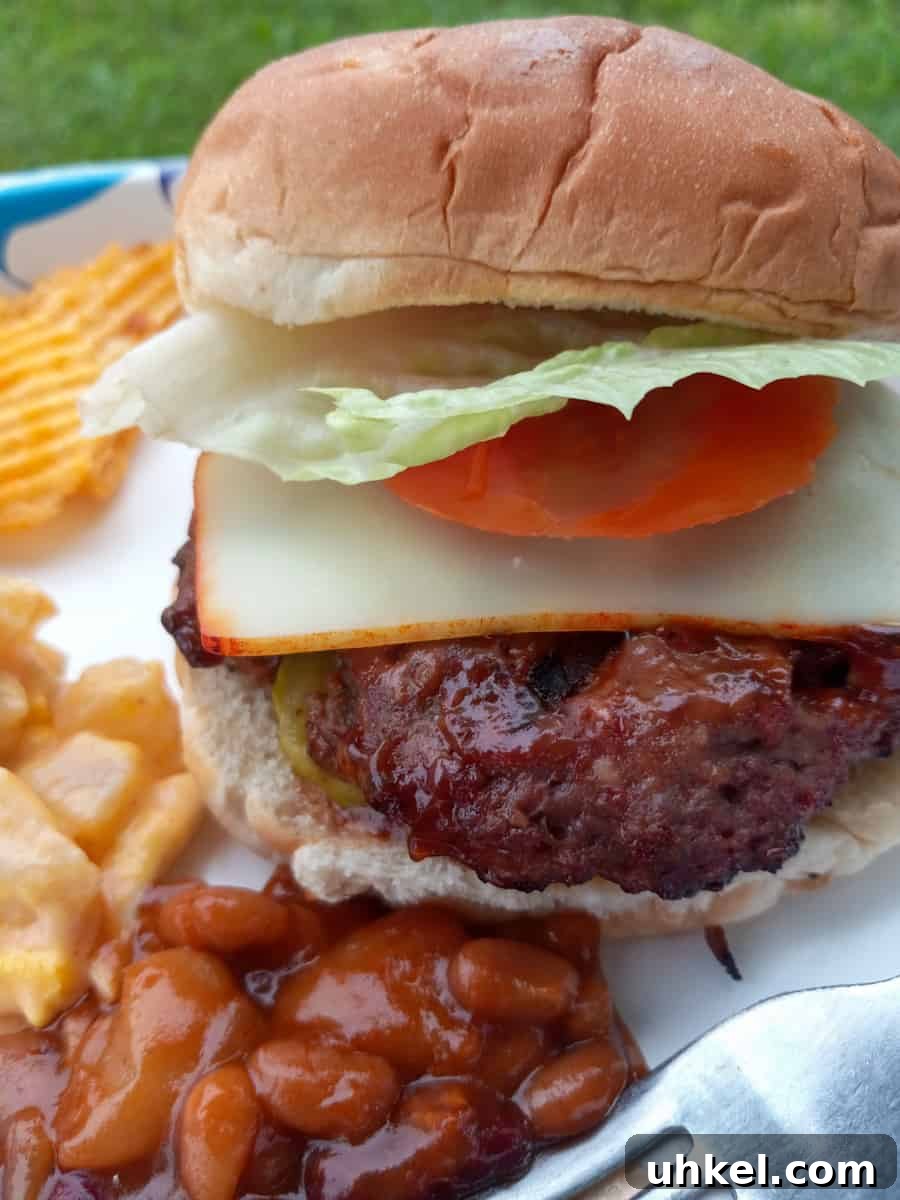 Amish-Style Grilled Burgers Recipe for Juicy Backyard BBQ 8 grilled barbecued hamburger on a plate with baked beans potato salad and chips