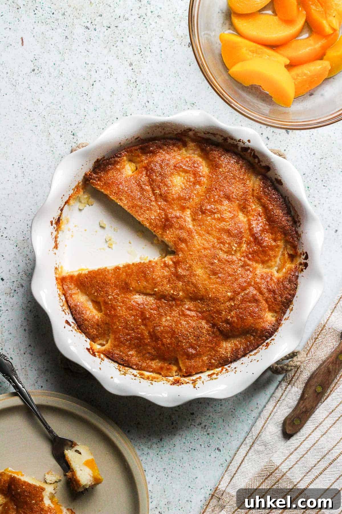 Classic Southern Peach Cobbler Recipe — Homemade & Fruity 2 peach cobbler in a pie dish with sliced peaches