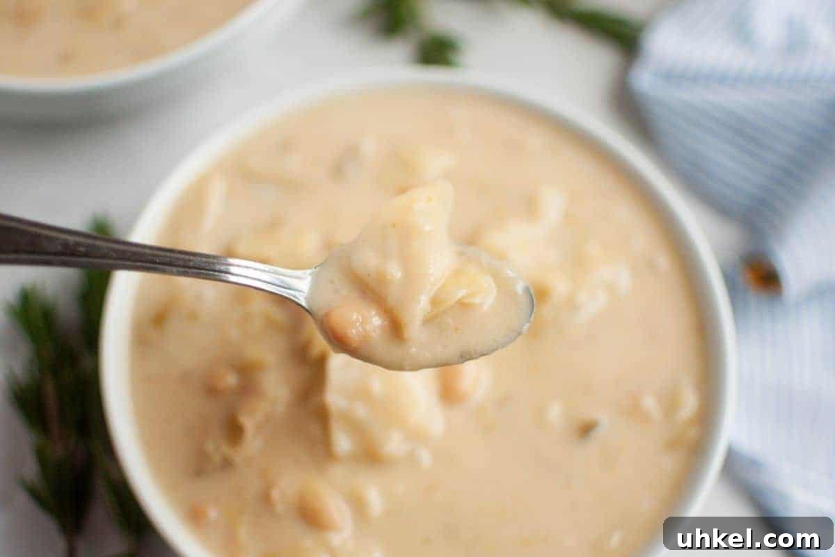 19 Budget-Friendly Dinners That Cut Your Grocery Bill (Delicious!) 4 A spoonful of creamy cabbage and white bean soup is held above a bowl.