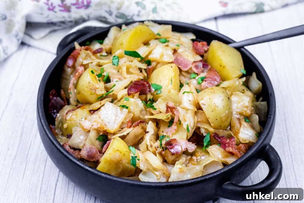 19 Budget-Friendly Dinners That Cut Your Grocery Bill (Delicious!) 6 A black bowl filled with Cabbage & Potatoes with Bacon with a spoon on the side.