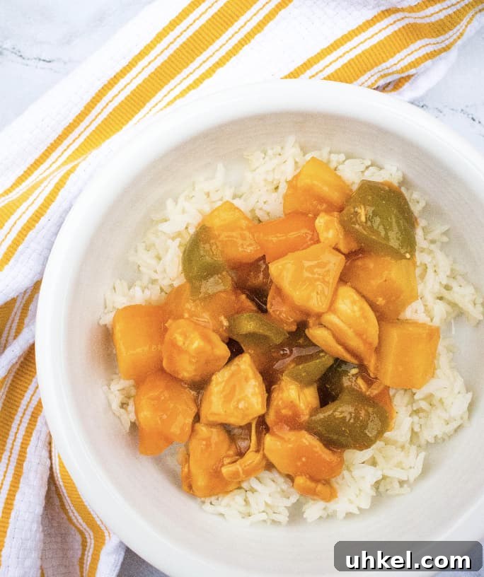 Instant Pot sweet and sour chicken over a bed of rice in a white bowl