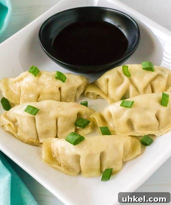 white plate serving Instant Pot frozen dumplings with green onions and soy sauce