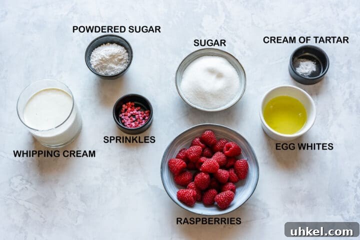 Heart-Shaped Mini Pavlovas: Valentine Dessert Recipe Ideas 3 Ingredients laid out for pavlova hearts: egg whites, sugar, cream of tartar, raspberries, whipping cream, powdered sugar, sprinkles.