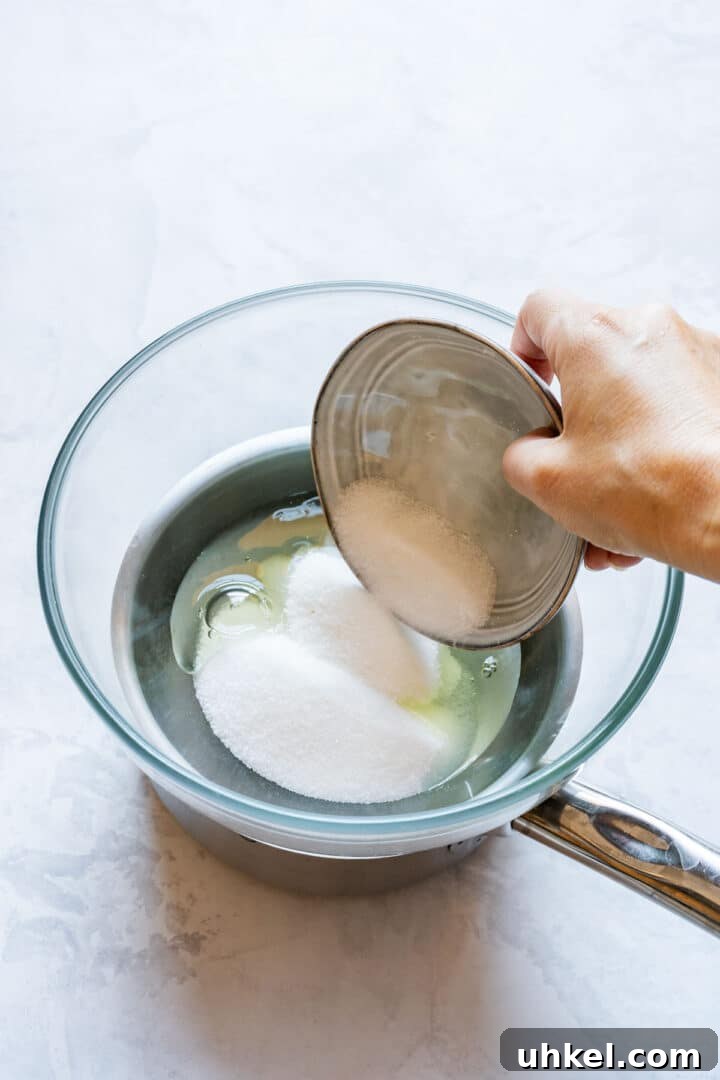 Heart-Shaped Mini Pavlovas: Valentine Dessert Recipe Ideas 4 Adding sugar to egg whites in a heatproof bowl set over simmering water.