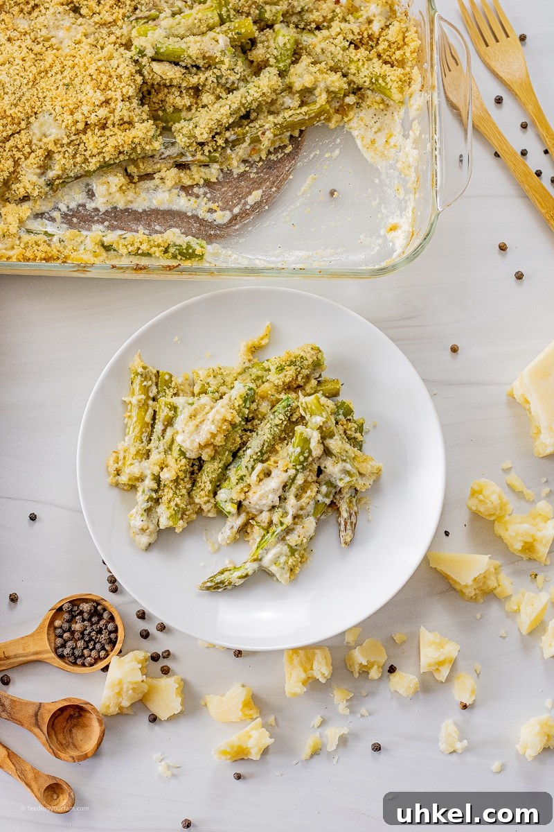 Crispy Baked Parmesan Asparagus Recipe 5 sliced asparagus in a cream sauce on a white plate