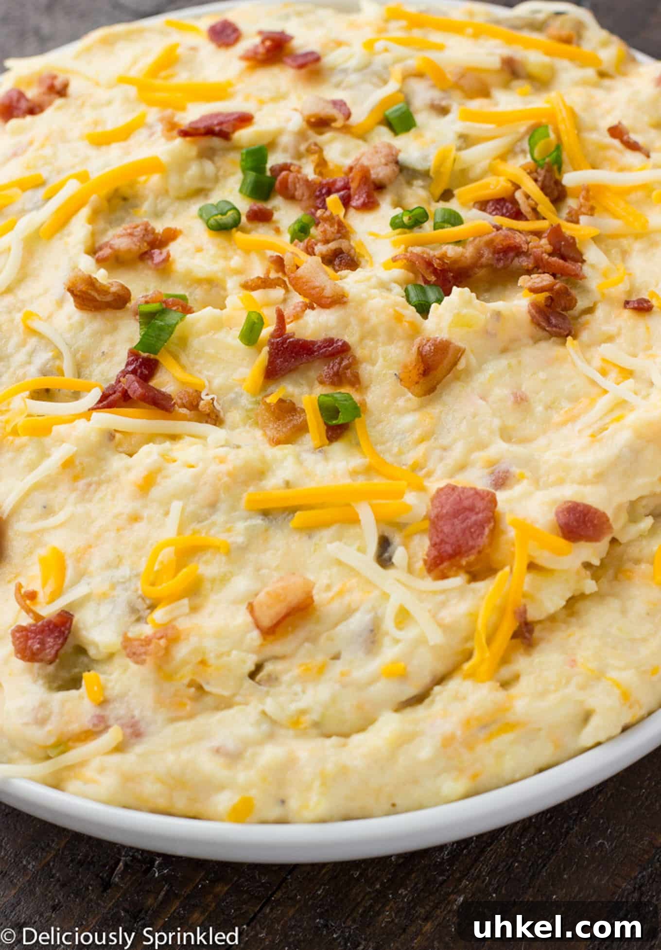 Creamy Instant Pot Mashed Potatoes Recipe 2 A bowl of instant pot mashed potatoes topped with a sprinkle of cheese, bacon, and green onions.