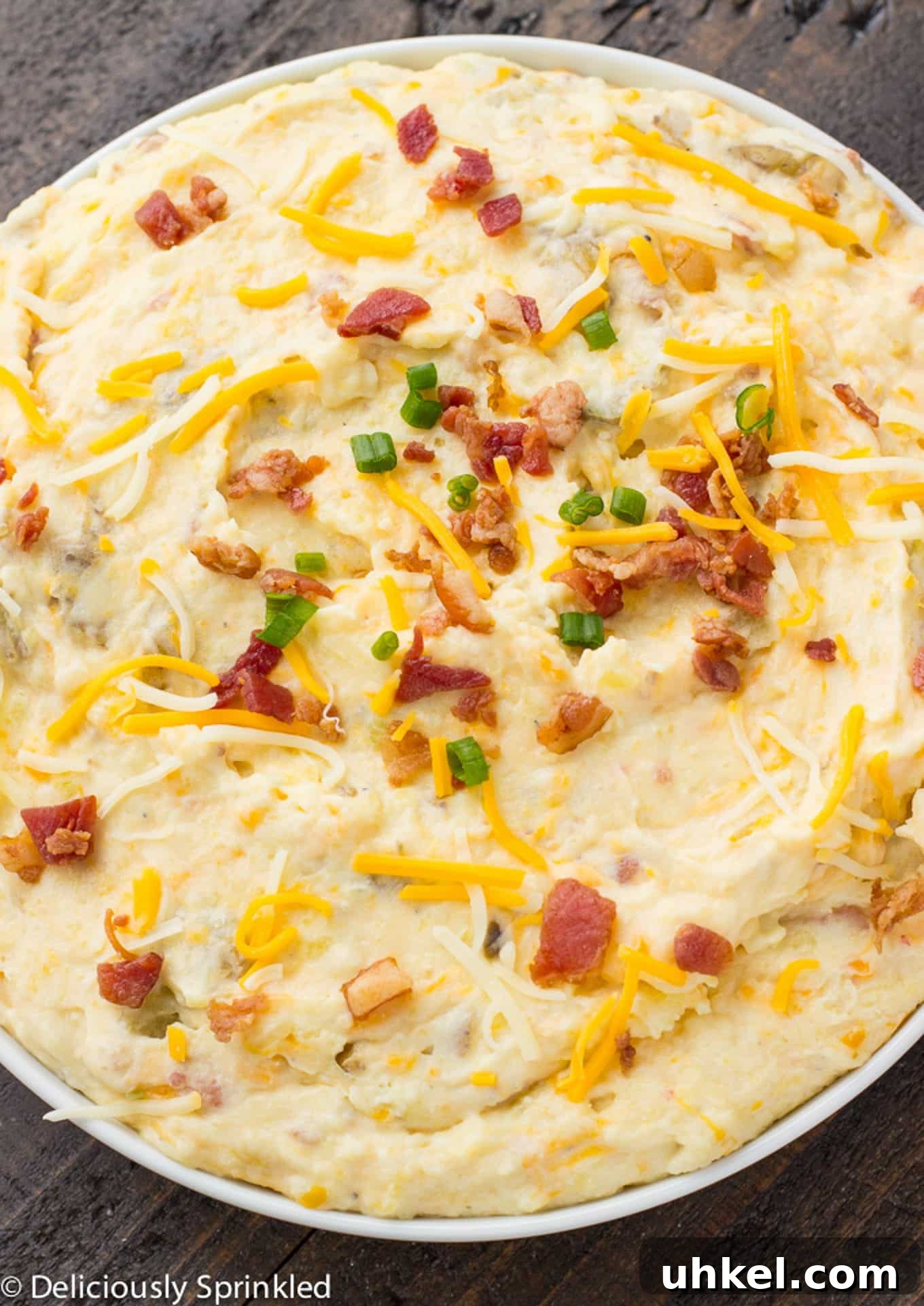 Creamy Instant Pot Mashed Potatoes Recipe 9 Loaded mashed potatoes topped with some bacon, cheese, and green onions in a serving bowl on the table.