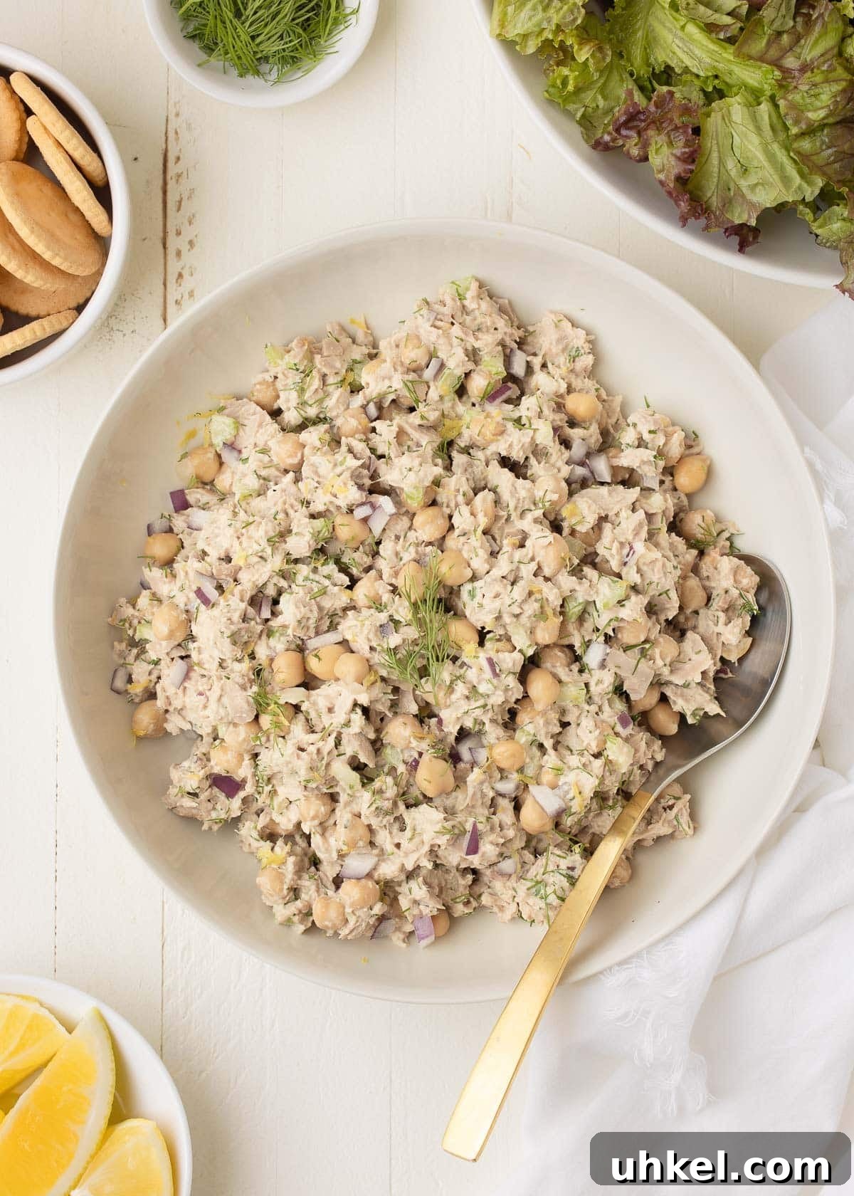 Tuna and Chickpea Salad with Lemon-Dill Dressing 2 A bowl of chickpea tuna salad with red onion, dill, lemon zest, lemon wedges, and salad greens.