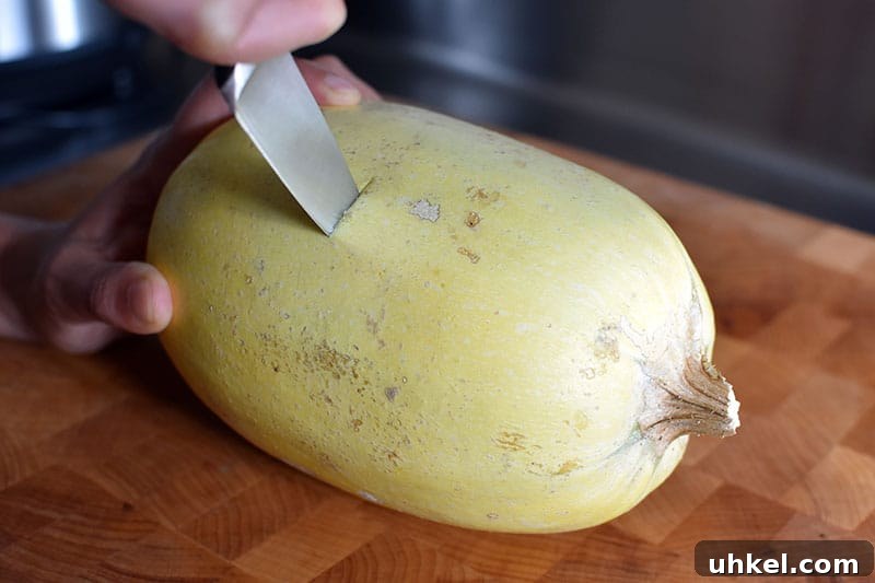 Instant Pot Spaghetti Squash — Quick Foolproof Pressure Cooker Recipe 6 A small spaghetti squash is lying on it's side on a cutting board. There's a small paring knife stuck in the middle of the spaghetti squash, cutting it in half horizontally.