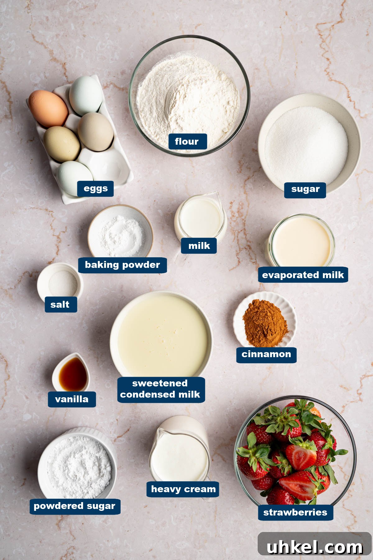 All of the ingredients for tres leches in bowls on a countertop.