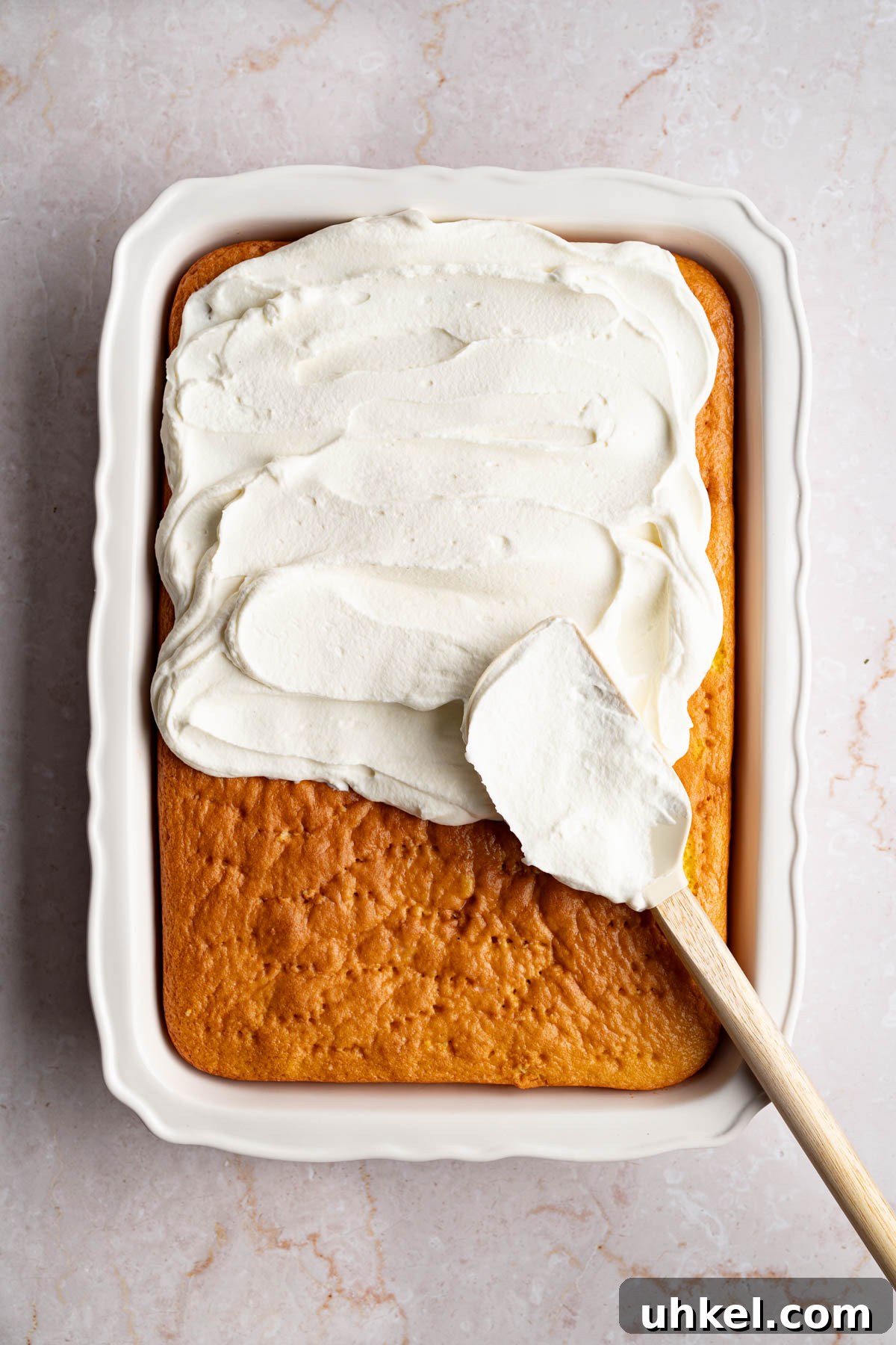 Spreading the whipped cream over the cake with a spatula.