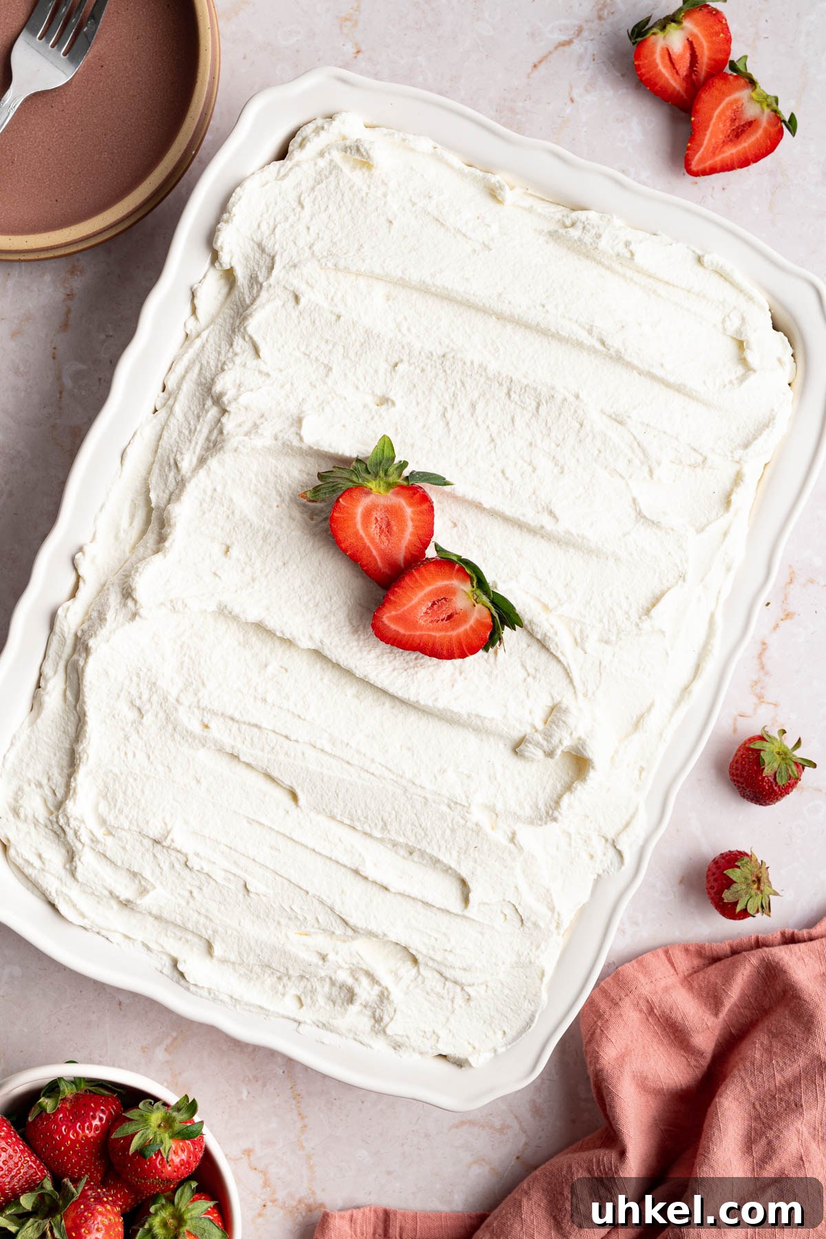 The cake decorated with the frosting and slices of strawberries.