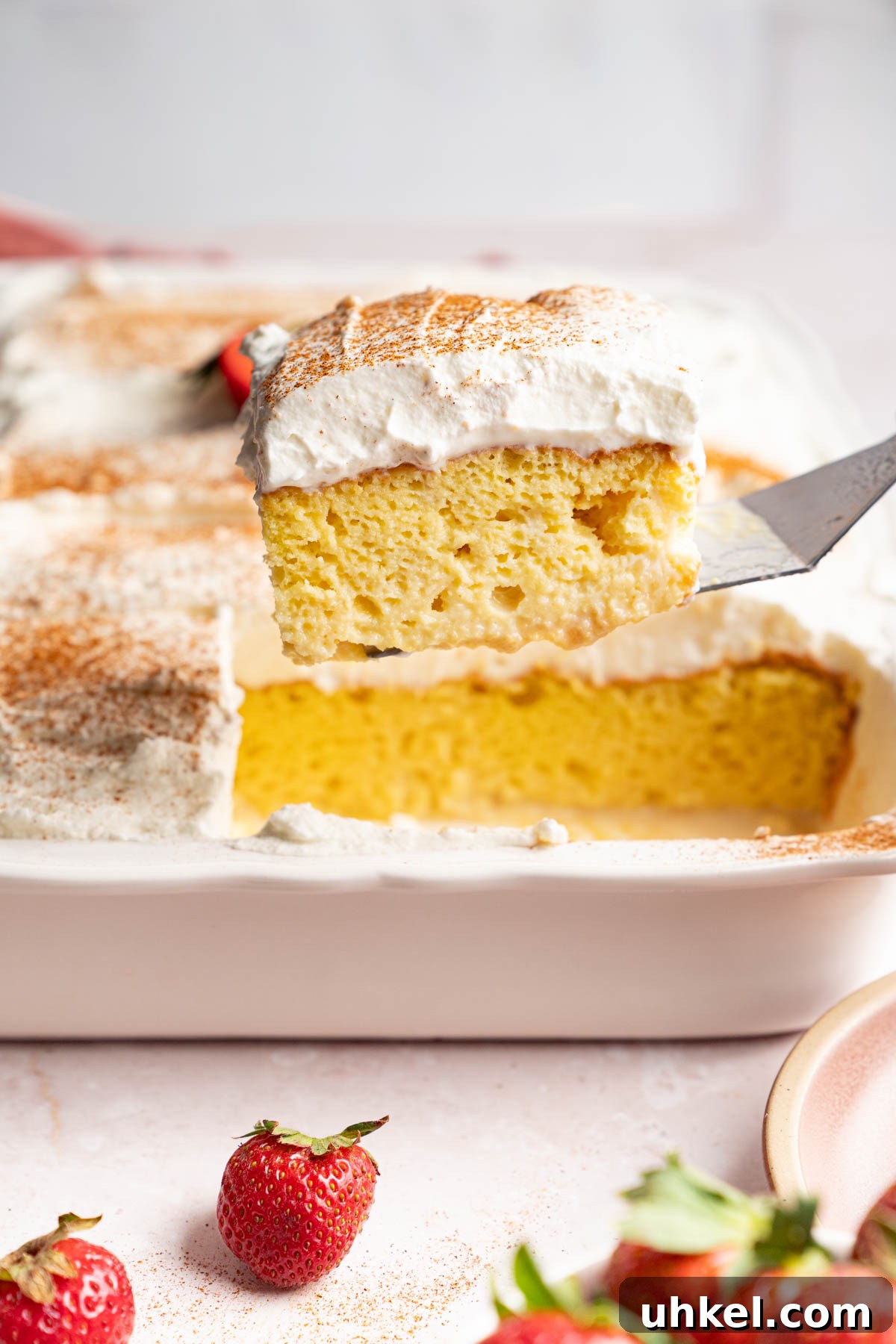 A serving spatula removes a piece of tres leches from the pan.
