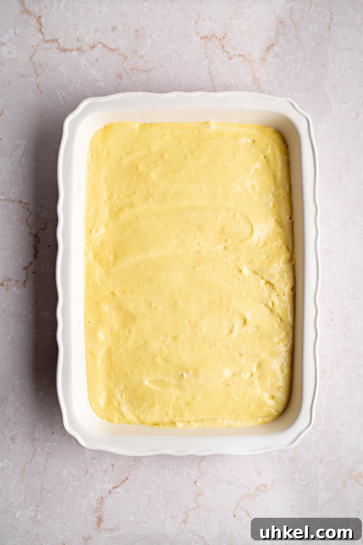The cake batter poured into the baking dish before baking.
