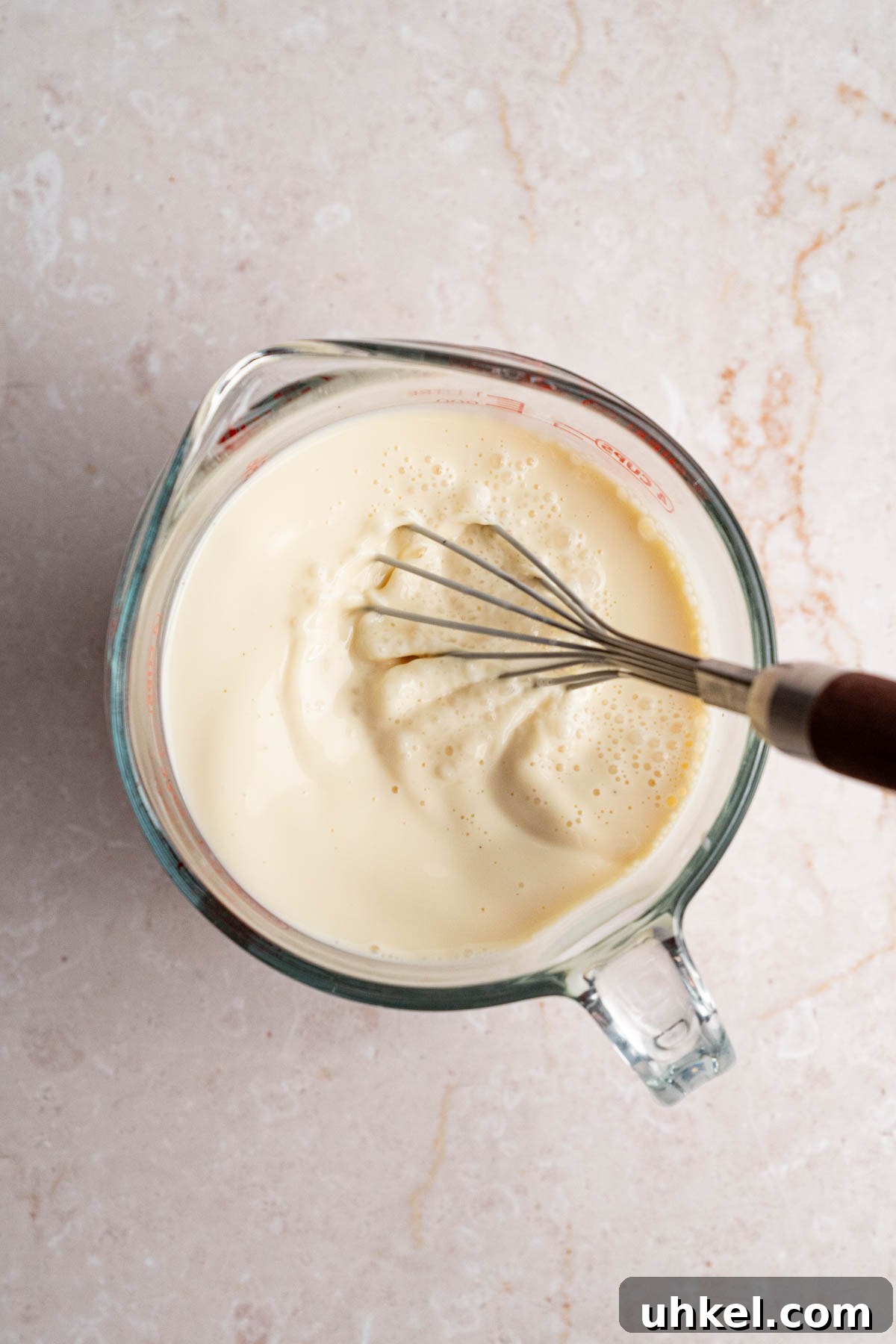 The milk mixture in a large bowl with a whisk after whisking together.