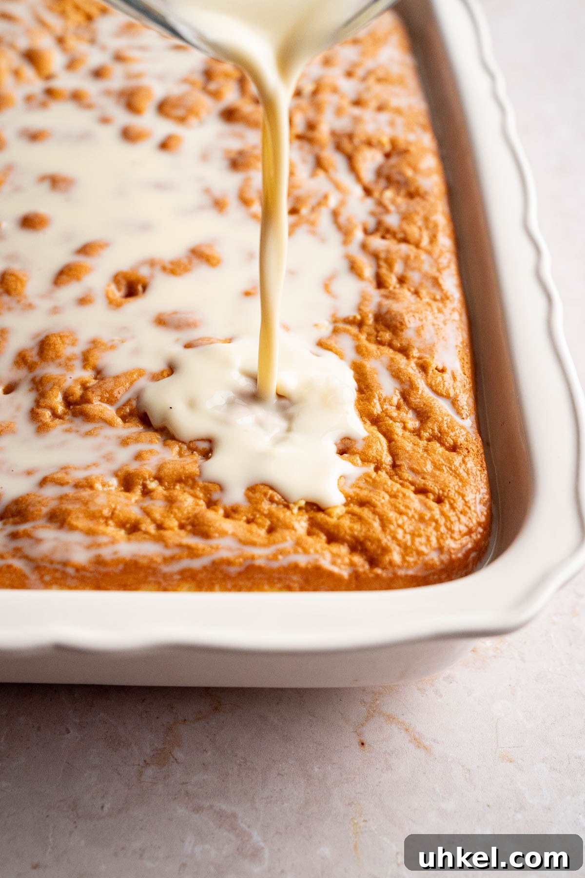 The milk mixture being poured over the cake. 