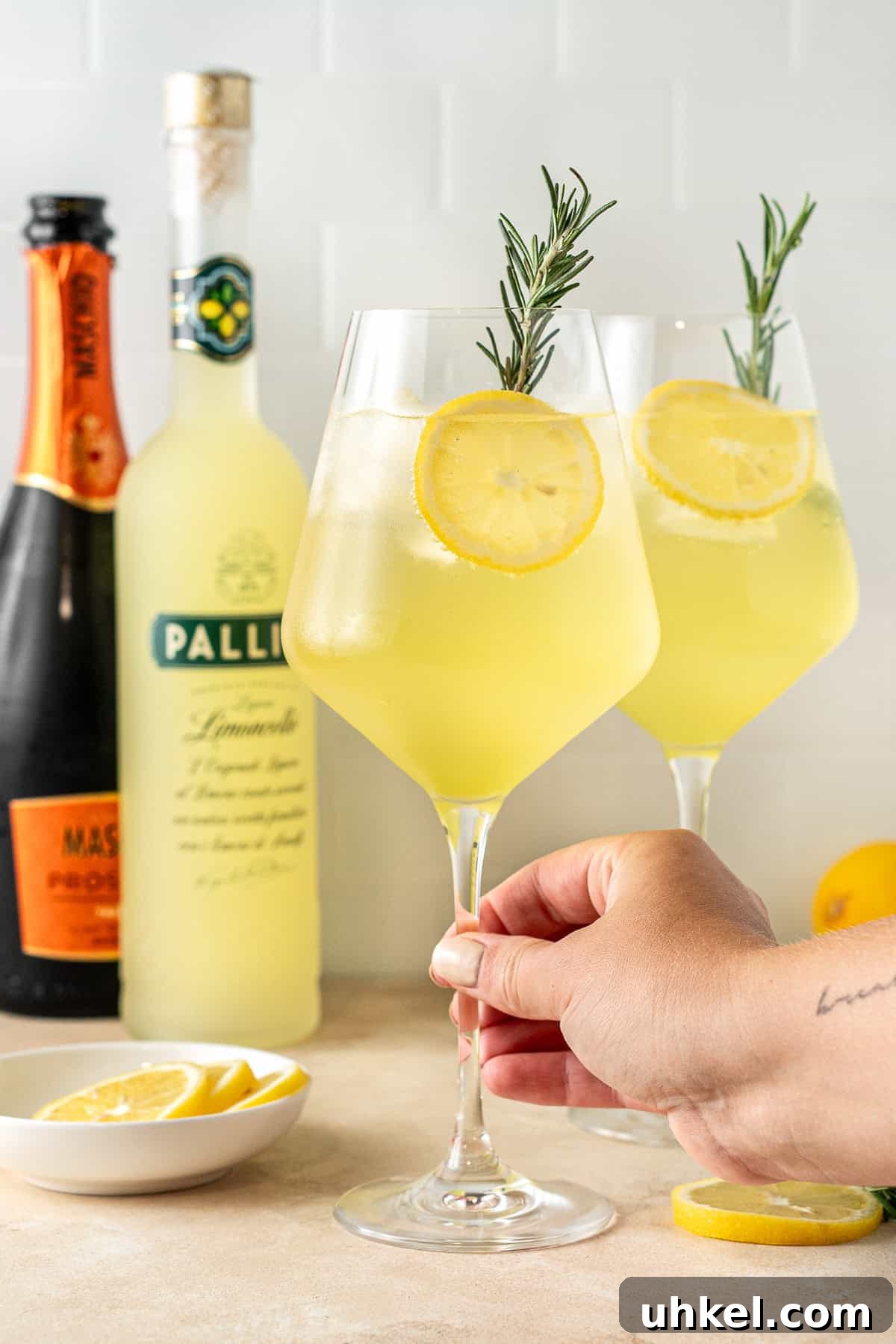 A hand holding the stem of the spritz glass. 