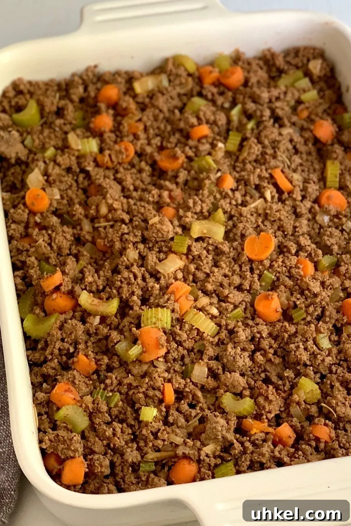 Dairy-Free Gluten-Free Shepherd's Pie Recipe for Comforting Dinner 2 A baking dish with cooked beef, onions, carrots, celery in it.