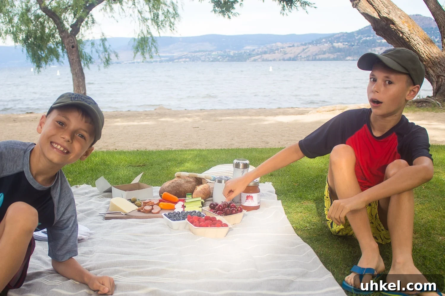 Two boys sitting next to a picnic by the beach