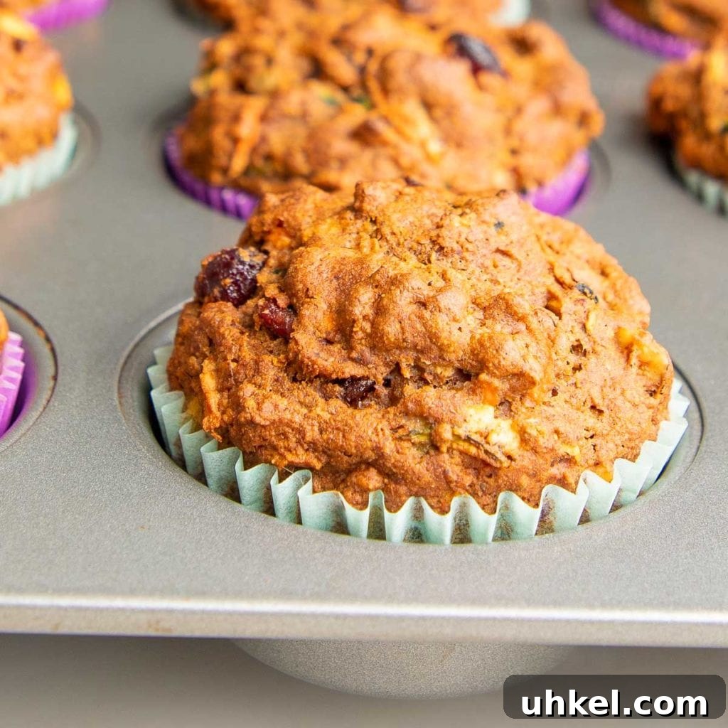 Morning Glory Muffins with Carrots, Apples & Nuts 8 close up of a morning glory muffin, still in the pan with a beautiful rise and crust, with a light blue liner.