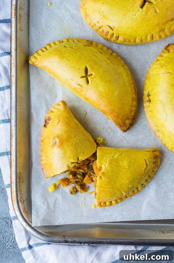 Vegan Jamaican Vegetable Patties: Flaky Caribbean Empanadas 7 Close up of vegan Jamaican vegetable pasties on a silver baking tray.