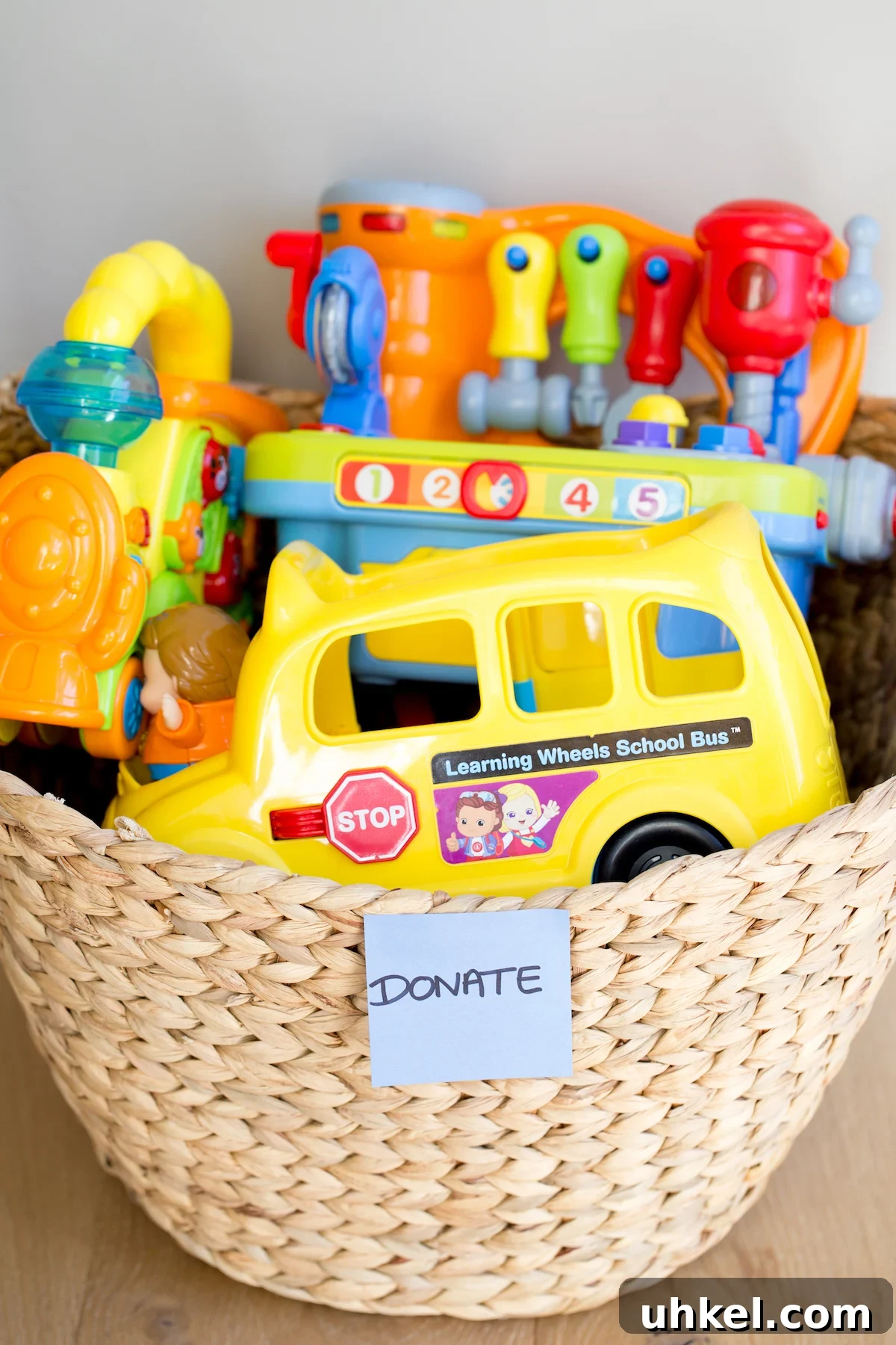 Declutter Kids' Toys: Simple Steps to Tidy Playrooms 9 closeup of plastic toys in a woven basket with a "donate" sticker on it