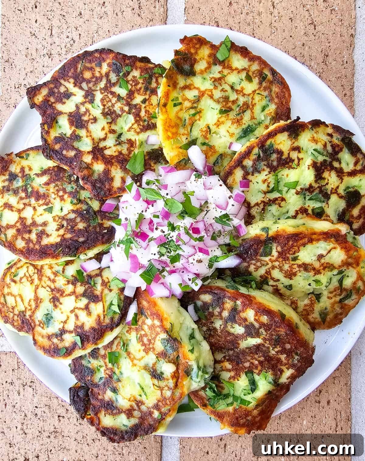 Crispy Garlic and Spinach Mashed Potato Cakes 5 prepared instant mashed potato cakes on plate with sour cream and red onion in the center