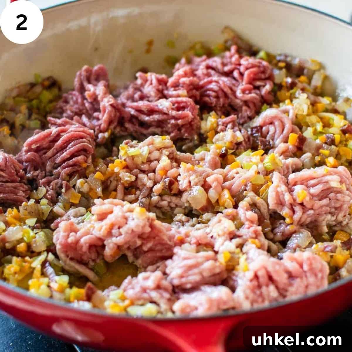 Authentic Tagliatelle alla Bolognese Recipe 5 Ground meat being sauteed in a pan with chopped vegetables.