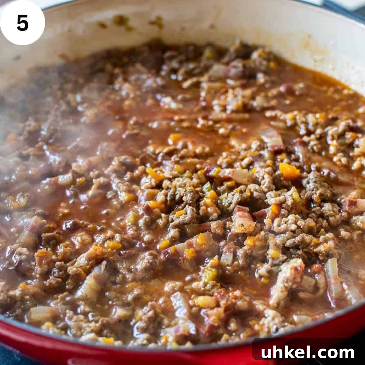 Authentic Tagliatelle alla Bolognese Recipe 8 Ground meat simmering in sauce in a round pan.