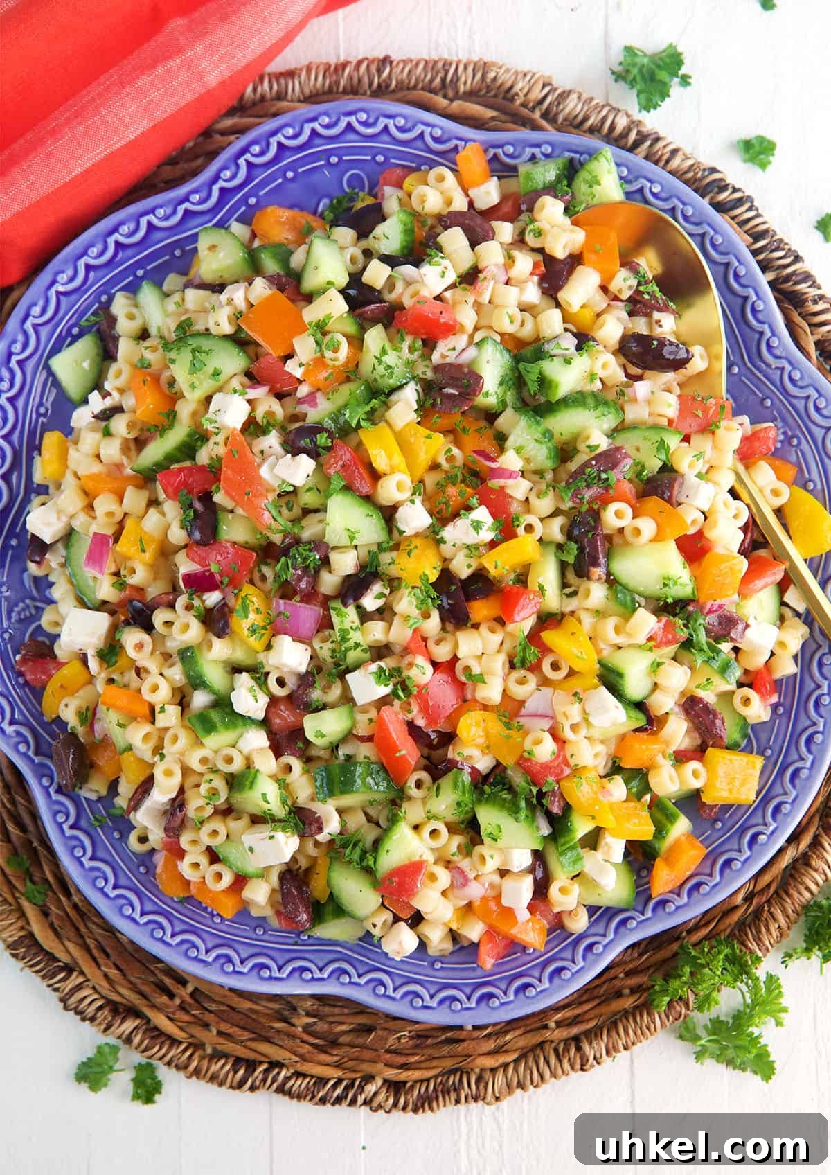 Greek Pasta Salad with Feta, Olives & Fresh Tomatoes 2 Greek Pasta Salad on a blue platter with a gold spoon.