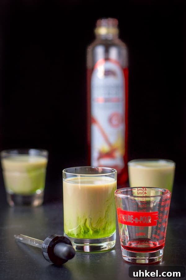 Mangled Frog Shot: 12 Christmas Shot Recipes 7 Grenadine in a little shot glass and a dropper beside it with the bottle in the background
