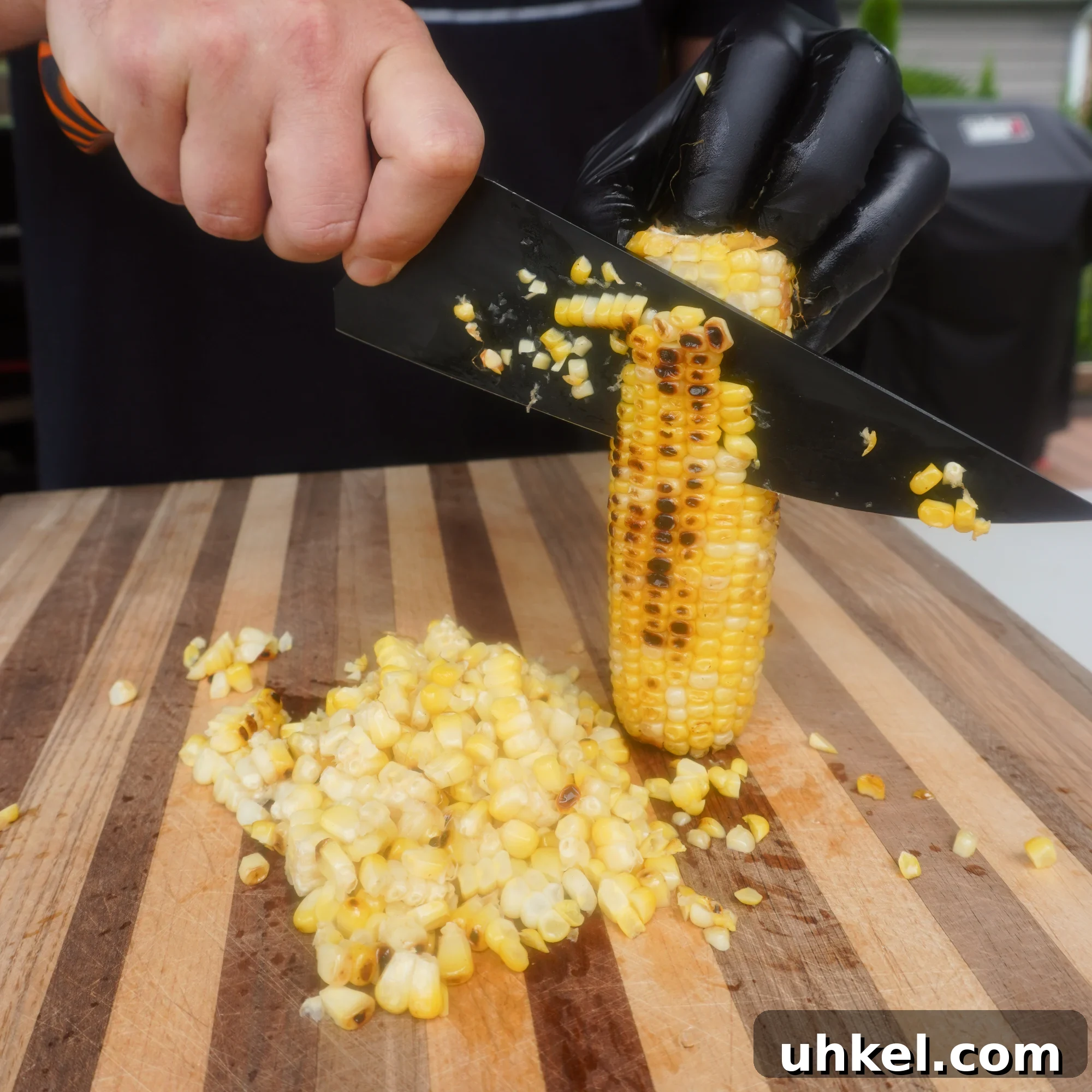 Grilled Shrimp Tacos with Zesty Corn Slaw 4 knife cutting off fire roasted kernels off corn on the cob.