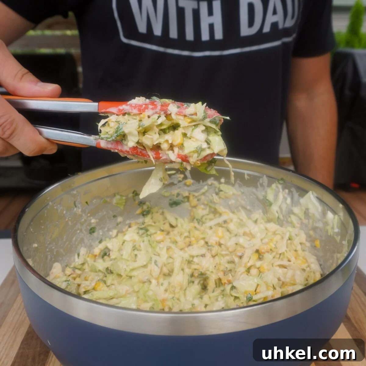 Grilled Shrimp Tacos with Zesty Corn Slaw 6 corn slaw mixed together in yeti bowl. Tongs showcasing a batch above the bowl for the grilled shrimp with corn slaw tacos.