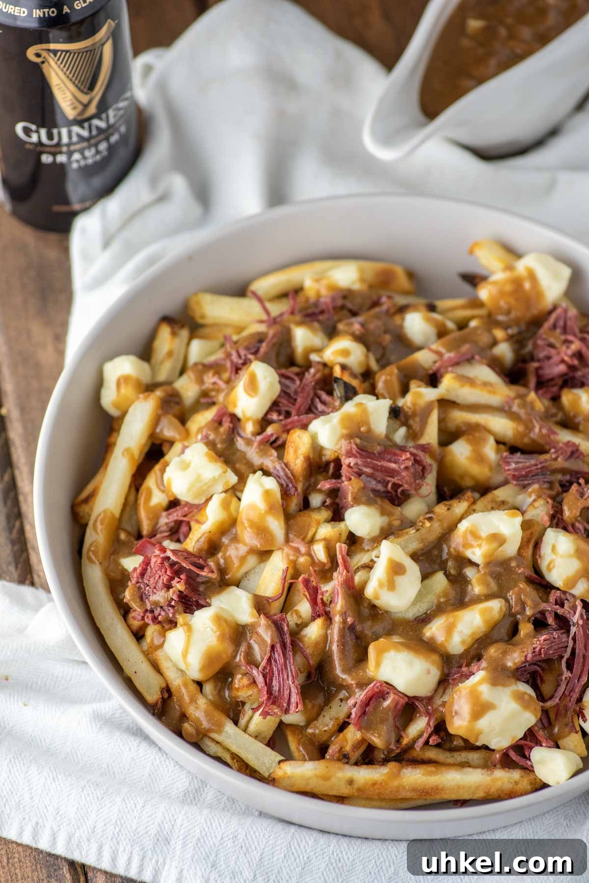 Corned Beef Poutine Topped with Guinness Gravy 5 poutine in bowl with gravy and Guinness in background