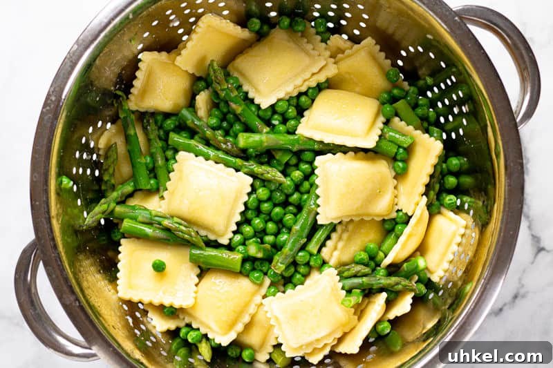 Spring Ravioli with Peas and Asparagus 4 Overhead shot of a metal strainer filled with cooked ravioli peas and asparagus