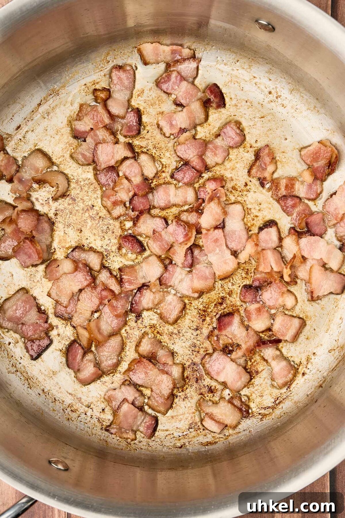 Smoky Fire-Roasted Tomato and Bacon Soup 4 Thick-cut bacon pieces browning in a stainless steel pot for fire-roasted tomato and bacon soup.