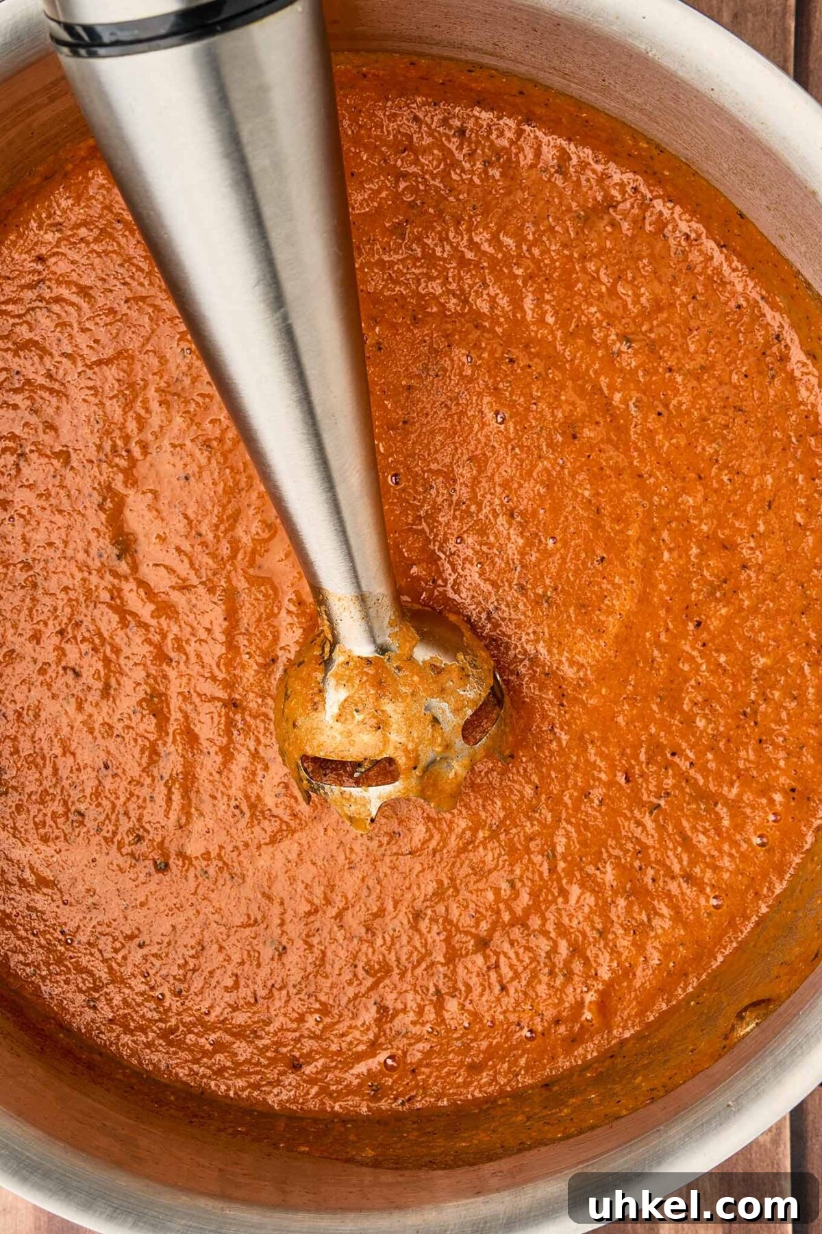 Smoky Fire-Roasted Tomato and Bacon Soup 7 Immersion blender puréeing fire-roasted tomato and bacon soup until smooth in a stainless steel pot.