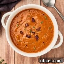 Smoky Fire-Roasted Tomato and Bacon Soup 10 A serving of fire-roasted tomato and bacon soup in a white bowl, garnished with bacon pieces and fresh thyme.