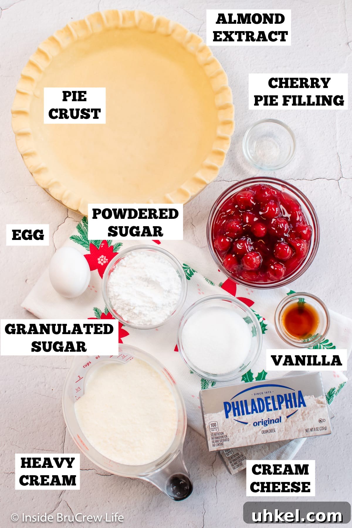 Classic Cherry Cream Cheese Pie Recipe 3 A white board with bowls of ingredients needed to make a pie with cheesecake.